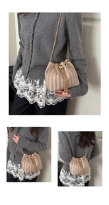 Detail showing woven texture on a beige bucket bag with gold chain and pearl drawstring