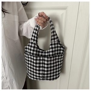 Detail view of black and white checkered canvas tote bag with front pockets and top handles