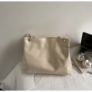 Détail d'un sac cabas crème en similicuir avec une finition brillante et bandoulière chaîne