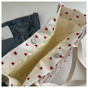 Detail of corduroy tote bag featuring heart print and internal magnetic snap closure