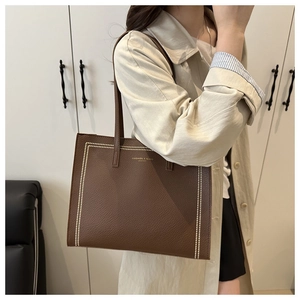 Detail of dark brown tote bag in pebbled leather with gold lettering for office commuting