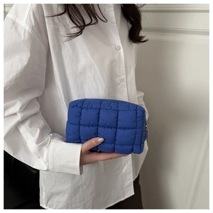 Close-up of royal blue quilted nylon cosmetic bag with square texture and gold zipper