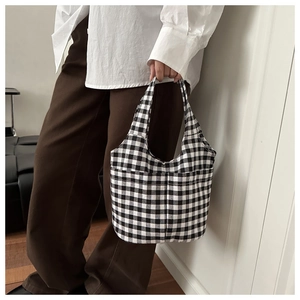 Detail shot of black and white gingham tote bag held by a model in casual outfit