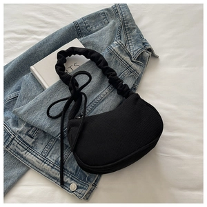 Détail du sac hobo en velours côtelé noir avec bandoulière plissée sur veste denim