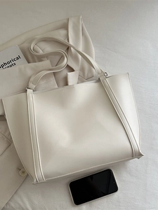 Minimalist beige oversized tote bag in faux leather on fabric with a white blazer