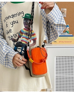 Détail du sac de téléphone orange et beige avec bandoulière tissée bicolore