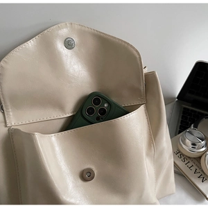 Détail de la poche avant de ce sac cabas en similicuir beige avec boucle magnétique en métal