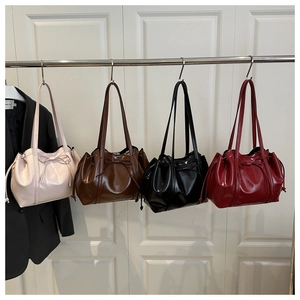 Four glossy tote bags in pink, brown, black, and red with drawstring bow details