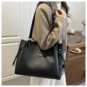 Dettaglio della borsa tote in pelle nera con anello metallico e doppi spallacci