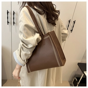 Close-up of brown litchi grain leather tote bag with white contrast stitching details