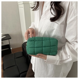 Detail showing bright green quilted nylon cosmetic bag texture and zipper closure