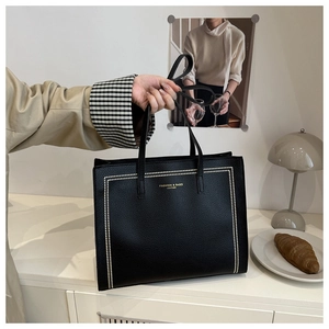 Detail of black tote bag featuring studded design and fashion lettering in a lifestyle setting