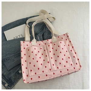 Detailed macro view of pink corduroy tote bag with heart print and front pockets