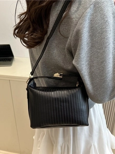 Modern black pleated handbag with vertical embossing and gold metal lock worn by a model