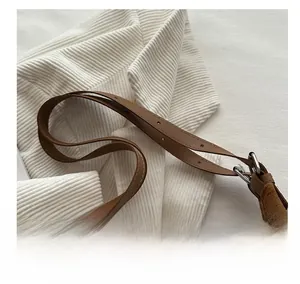 Detailed close-up of brown suede fabric and adjustable leather shoulder strap with stitching