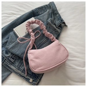 Gros plan d'un sac à épaule en velours côtelé rose avec bandoulière froncée chic