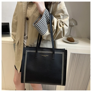 Close-up of black leather tote bag featuring gold lettering and elegant metallic accents