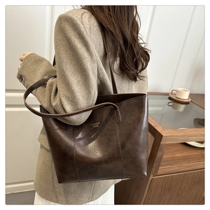 Detail view of large dark brown leather tote bag with Fashion Bags text on textured surface
