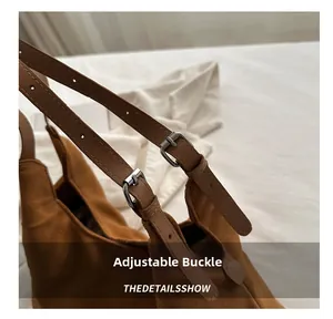 Detailed view of brown suede shoulder bag with adjustable strap and silver buckle
