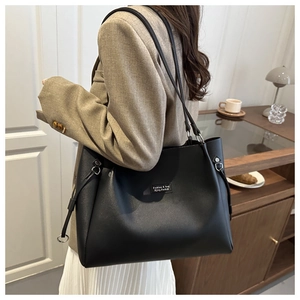 Dettaglio della grande borsa tote nera con coulisse ad anello metallico ed etichetta