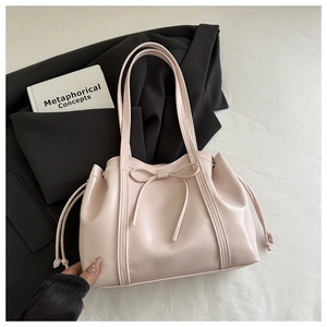 Close-up of pink tote bag with leather bow detail and adjustable side drawstring