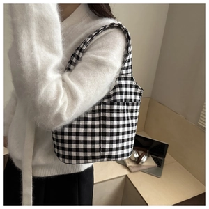 Detail of checkered canvas bucket bag with side pocket in a minimalist desk setting