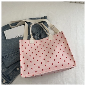 Detail of light pink corduroy tote bag featuring red heart patterns and canvas straps