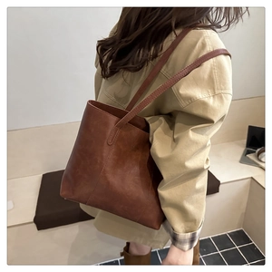 Detail of a large brown vintage tote bag showing retro leather texture and shoulder straps
