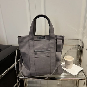 Dark grey canvas tote bag with adjustable strap and front zipper pocket for urban commute