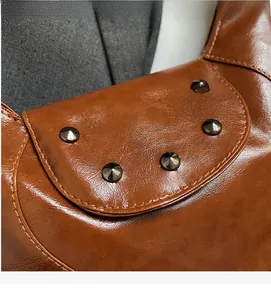 Detailed close-up of brown pebbled leather texture and retro metal rivets on a saddle bag