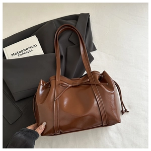 Detail of brown glossy PU tote bag with drawstring closure and bow decoration