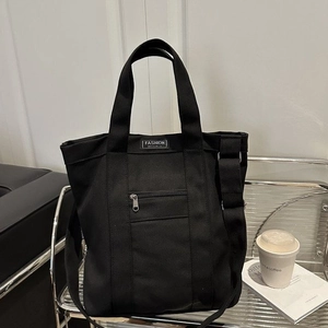 Black canvas tote bag with FASHION INSTINCT label and outer zipper pocket for daily commute
