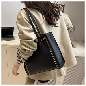 Detail of black leather tote bag with contrast stitching on professional female model