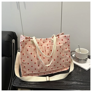 Close-up of pink corduroy tote bag with red heart pattern and dual front pockets