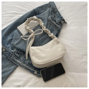 Détail du sac sous le bras en velours côtelé blanc cassé avec broderie nœud rose