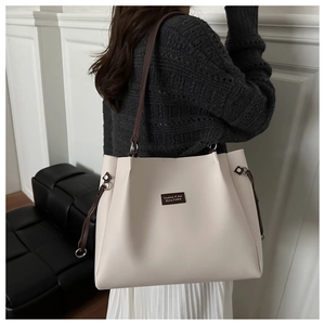 Dettaglio della borsa tote grande in pelle color crema con tracolle marroni a contrasto