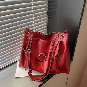 Détails du nœud argenté et de la texture cuir brillant sur un sac fourre-tout rouge