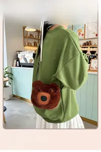 Detailed view of plush brown bear shaped crossbody bag worn by a model in a cozy cafe