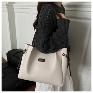 Dettaglio della borsa tote beige grande con spalline marroni e toppa con logo