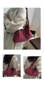 Detail of burgundy faux suede shoulder bag with adjustable strap worn on beige coat
