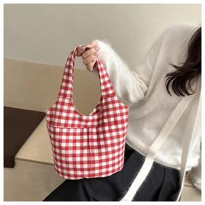 Close-up of red and white checkered canvas bucket bag with soft pleated texture and handle