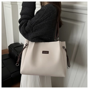Dettaglio della grande borsa tote beige con tracolle marroni e coulisse sul modello