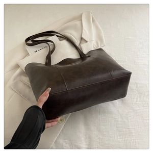 Detail of dark brown leather tote bag with gold fashion text in a stylish setting