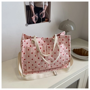 Detail of pink corduroy tote bag with red heart pattern and dual front pockets