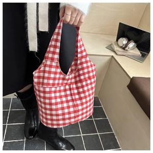 Detailed close-up of a red and white checkered canvas tote bag with a practical outer pocket