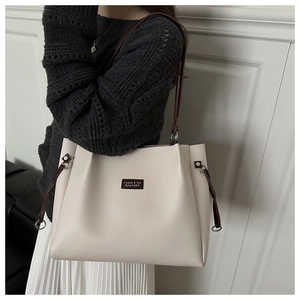 Dettaglio della grande borsa tote crema con cinturini marroni e patch in ecopelle