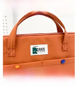 Vue de face d'une sacoche d'ordinateur orange avec doubles poches et boutons contrastés