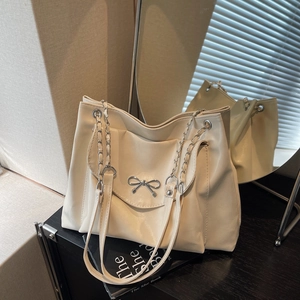 Vue détaillée du sac cabas blanc crème avec nœud en métal argenté et bandoulière chaîne