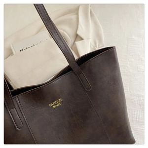 Detailed view of dark brown vintage tote bag with gold FASHION BAGS text and leather texture