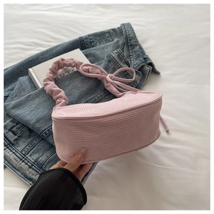 Détail du sac à bandoulière en velours côtelé rose avec poignée froncée et nœud latéral